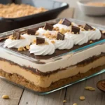 Close-up view of an enticing Peanut Butter Lasagna layered dessert with chocolate ganache, smooth peanut butter filling, and whipped cream on a white plate.