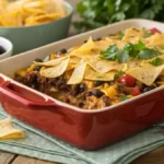 A freshly baked COWBOY CASSEROLE with melted cheese and tortilla chip topping in a baking dish.