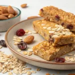 Homemade Granola Bars on a wooden table with oats and nuts scattered around.