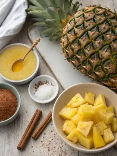 Fresh pineapple slices with honey and cinnamon on a kitchen table.