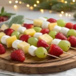 Colorful Christmas fruit kabobs on a wooden platter with strawberries, grapes, pineapple, melon, and marshmallows.