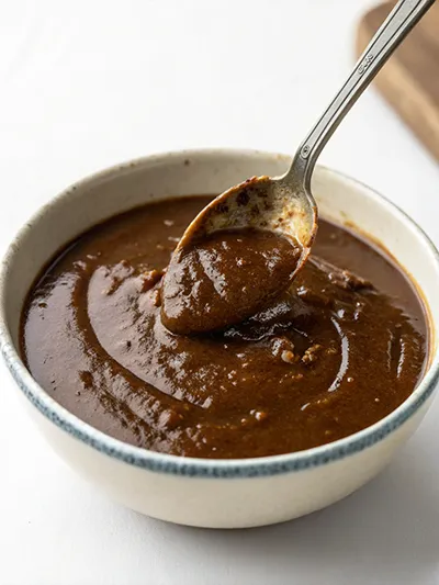 Bowl of thick vegan gravy with a spoon, showing a smooth, glossy texture.
