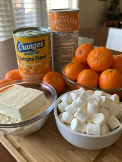 A colorful assortment of ingredients for orange fluff dessert on a kitchen table.