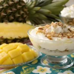 A delicious bowl of pineapple delight dessert with coconut and pecans, garnished with fresh pineapple slices.