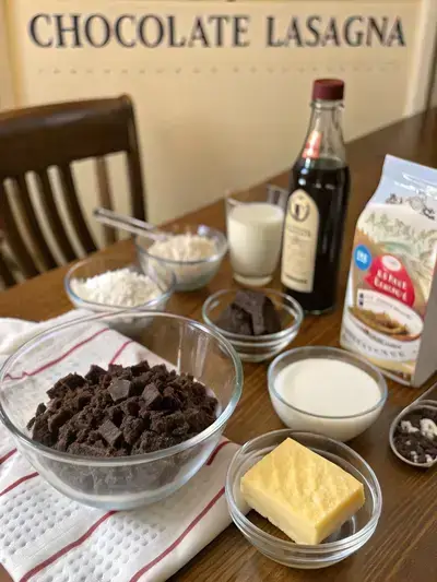 Ingredients for CHOCOLATE LASAGNA displayed on a kitchen table, including Oreo cookies, cream cheese, and chocolate pudding mix.